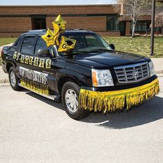 a black truck parked in front of a building with yellow decorations on it's hood