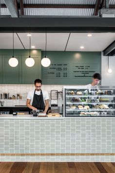 two men working behind the counter in a restaurant or cafe with wood floors and green walls