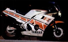 an orange and white yamaha motorcycle parked on the street