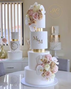 three tiered wedding cake with pink and white flowers on the top, sitting on a table