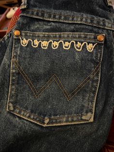 the back pocket of a pair of blue jeans with gold trimmings on them