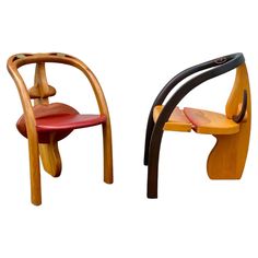 two wooden chairs sitting side by side on a white background, one is red and the other is black