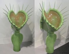 two green vases with spikes on them in the shape of heart shaped flowers and leaves