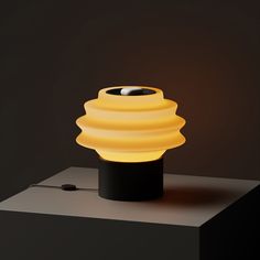 a yellow lamp sitting on top of a black table next to a white light bulb