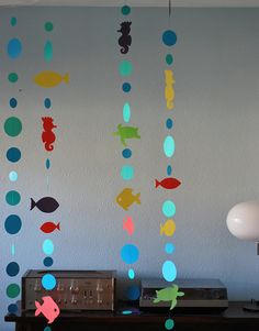 a room with some decorations hanging from the ceiling and fish in the water on the wall