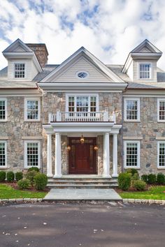 a large stone house with white trim and columns on the front door is pictured in this image