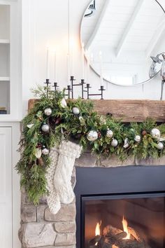 a fireplace decorated for christmas with greenery and stockings hanging over the mantels