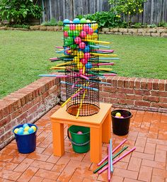 a bird cage filled with balls and sticks on top of a wooden table next to buckets