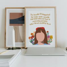 a white laptop computer sitting on top of a desk next to a framed poster with a woman's face