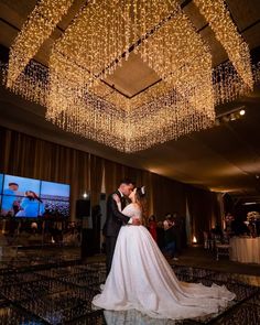 a bride and groom kissing under a chandelier