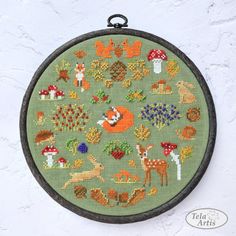 a cross - stitch pattern with animals and mushrooms in the center on a green background