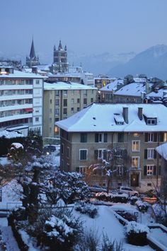 the city is covered in snow and has tall buildings with towers on each side that are lit up at night