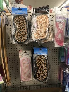 several pairs of animal print slippers are on display in a shoe store with plastic bags