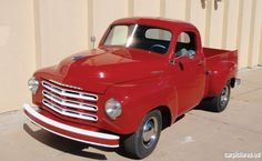 an old red truck parked in front of a building