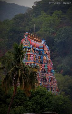 a very tall colorful building sitting on top of a lush green hillside next to trees