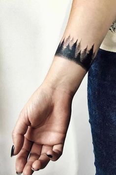 a person's arm with a tattoo on it that has mountains in the background