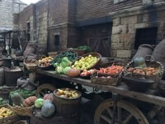 an outdoor market with lots of fruits and vegetables on the tables in front of brick buildings