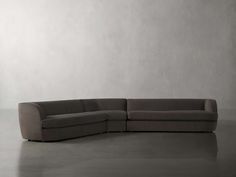 a gray couch sitting on top of a floor next to a white wall in an empty room