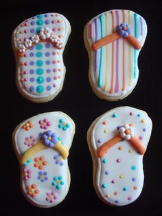 four decorated cookies in the shape of flip flops and sandals on a black background