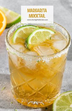 a close up of a drink in a glass with ice and lime