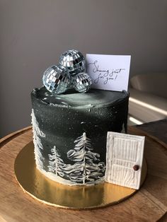 there is a black and white cake with silver decorations on the top that has a note attached to it