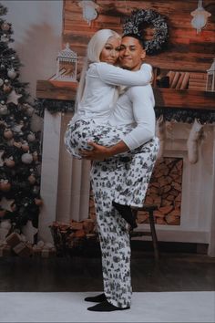 a man and woman hugging in front of a christmas tree