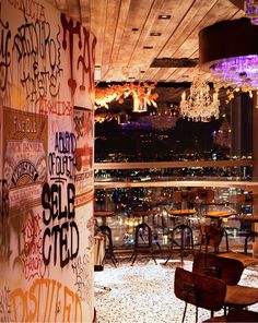 the interior of a restaurant with lots of graffiti on the walls and tables in front of it