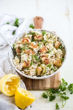 a bowl filled with rice and shrimp next to lemon wedges