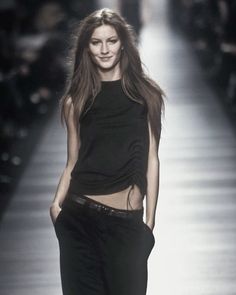 a woman walking down a runway in black clothes