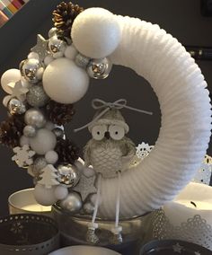 an owl sitting on top of a wreath with balls and ornaments around it's neck