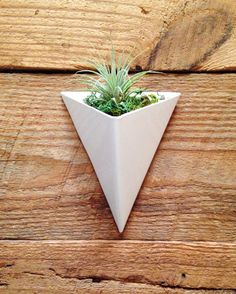 a small white planter sitting on top of a wooden table next to a wall