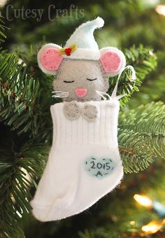 an ornament hanging from a christmas tree with a mouse in it's sock