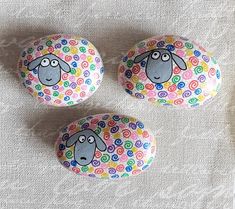 three painted rocks with sheep faces on them