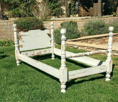 an old white bed frame sitting in the grass