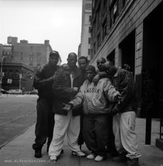 black and white photograph of five people standing on the sidewalk