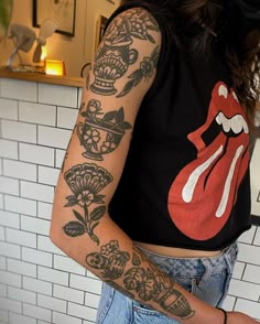 a woman with tattoos on her arm and chest standing in front of a tiled wall