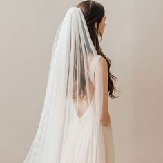 the back of a bride's wedding dress with a long veil on her head