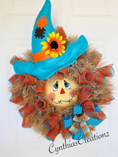 an orange and blue scarecrow wreath with a sunflower on top