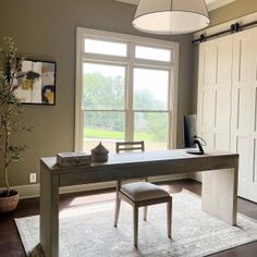 a room with a table, chair, and window in the center is lit by a light fixture