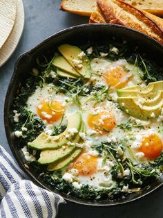 an egg and avocado dish in a cast iron skillet with bread on the side