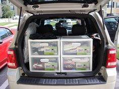 the back end of a white car with its trunk open and two clear plastic drawers