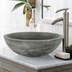 a bowl sink sitting on top of a bathroom counter next to a faucet