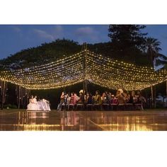 a bride and groom standing under a canopy covered in fairy lights at their wedding reception