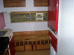 a small kitchen with red cabinets and white walls, along with an open window to the outside