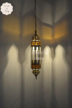 a light hanging from a chain in a room with white walls and shadows on the wall