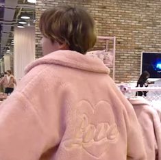 a woman in a pink robe is looking at a computer screen and she has her back turned to the camera