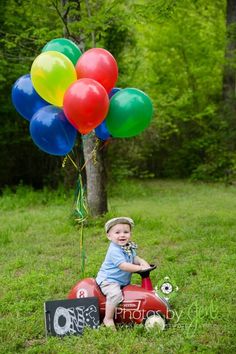 a little boy sitting on top of a red motorcycle with balloons attached to it's back