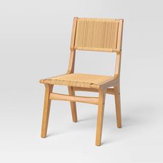 a wooden chair with wicker seat and back rests on a white surface, in front of a gray background