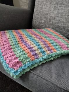 a crocheted blanket sitting on top of a couch next to a gray chair