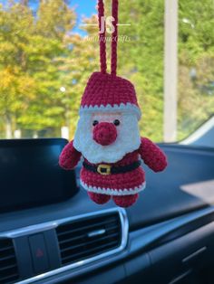 a stuffed santa claus hanging from the dashboard of a car